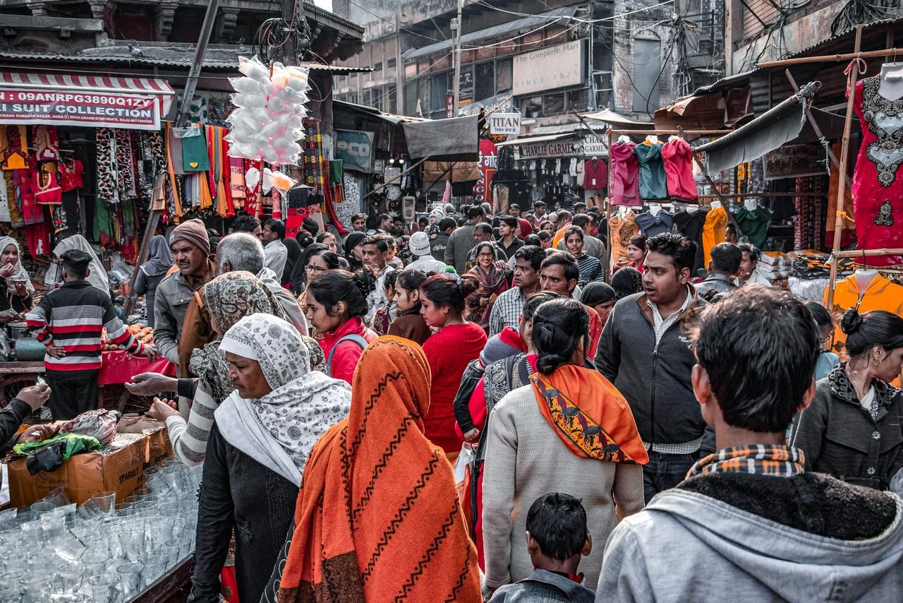 A crowded street market filled with people shopping in an urban environment.